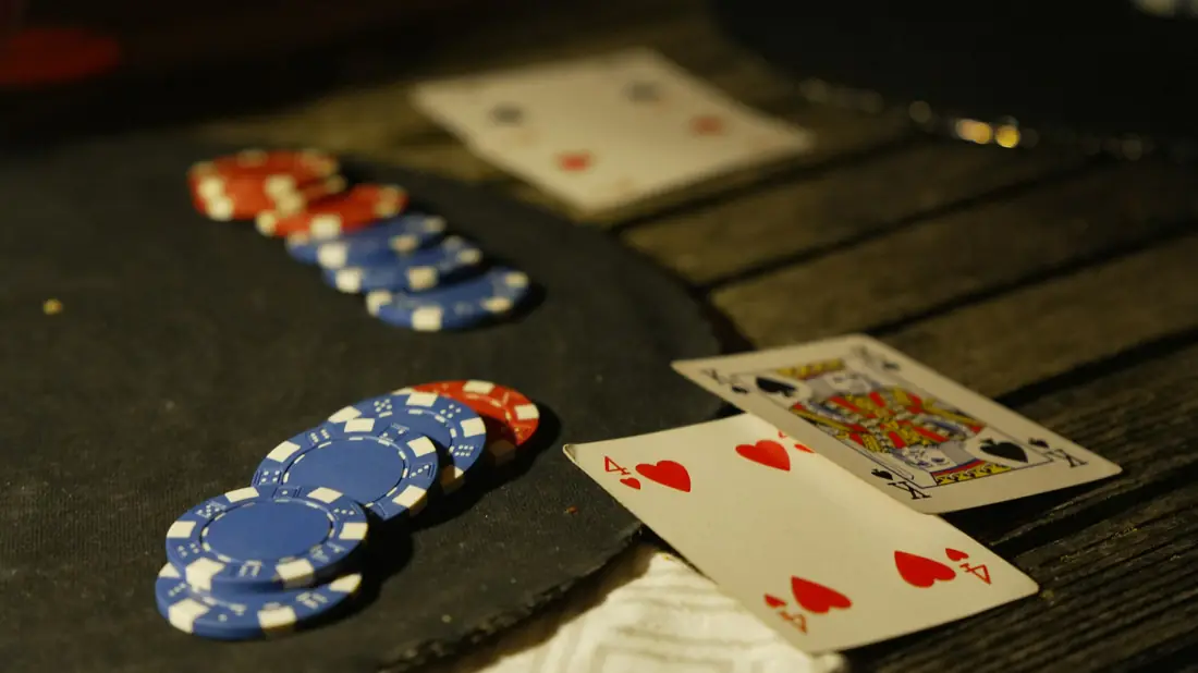 Kartu poker tersebar di atas meja hijau bertumpuk chip
