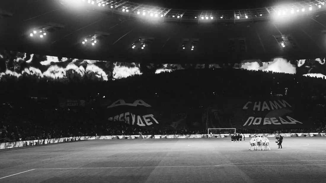 Stadion sepak bola hijau dengan lampu sorot menyala malam